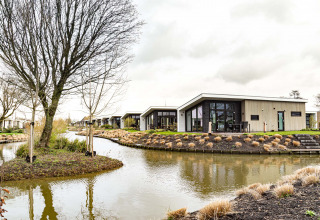 Hyggelige feriehytter ved en fredelig kanal i Park Westerkogge, Nordholland, med moderne arkitektur.