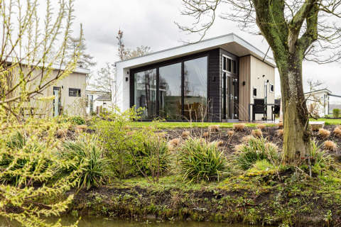 Bungaló de vacaciones moderno rodeado de plantas y agua en Park Westerkogge, en Holanda Septentrional, Países Bajos.