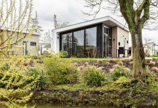 Bungaló de vacaciones moderno rodeado de plantas y agua en Park Westerkogge, en Holanda Septentrional, Países Bajos.