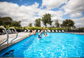 Twee kinderen springen in het openluchtzwembad van Park Westerkogge, een vakantiepark in Noord-Holland, Nederland.