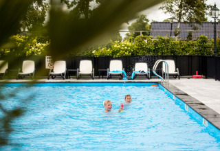 Twee kinderen spelen in het buitenzwembad van Park Westerkogge, een vakantiedomein in Noord-Holland, Nederland.