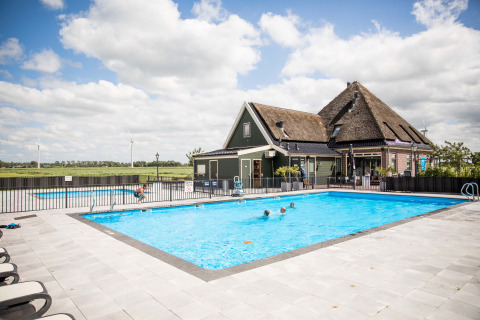 Piscina al aire libre en Park Westerkogge, parque vacacional en Holanda Septentrional, con familia y paisaje rural.