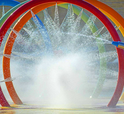 Aros de agua coloridos y chorros en la zona de juegos acuáticos de Camping Village Baia Blu La Tortuga, Cerdeña.