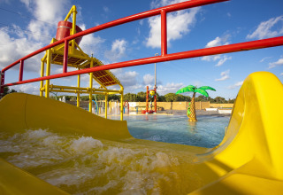 Water playground with yellow slides and splash features at Camping Village Baia Blu La Tortuga in Sardinia, Italy.