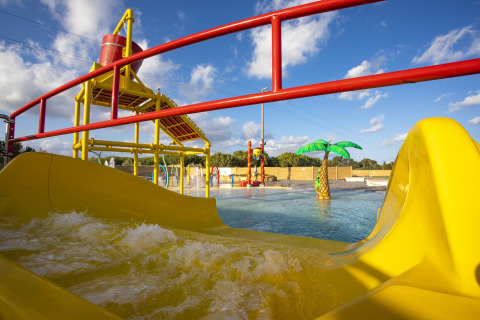 Water playground with yellow slides and splash features at Camping Village Baia Blu La Tortuga in Sardinia, Italy.