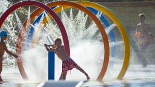 Niños juegan en el parque acuático con aros de colores y fuentes en Camping Village Baia Blu La Tortuga, Cerdeña.