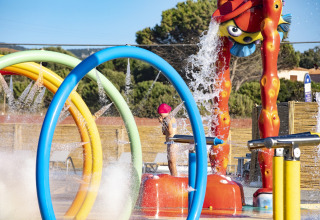 Children play at a colorful splash park in Camping Village Baia Blu La Tortuga holiday park in Sardinia, Italy.