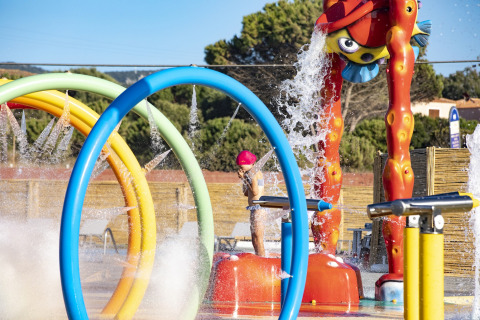 Kinderen spelen in een kleurrijk waterspeelpark op Camping Village Baia Blu La Tortuga in Sardinië, Italië.