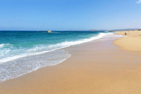 Playa de arena dorada con aguas turquesas y cielo azul cerca de Aglientu, Cerdeña, Italia, en un tranquilo día de verano.