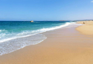 Playa de arena dorada con aguas turquesas y cielo azul cerca de Aglientu, Cerdeña, Italia, en un tranquilo día de verano.