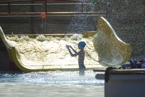 Child playing in water spray at a waterslide in Camping Village Baia Blu La Tortuga, Sardinia, Italy.