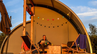 Hombre relajándose con un libro en la terraza de Panorama Lodge en Holiday Park Mölke, Países Bajos