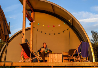 Man ontspant zich met een boek op het terras van Panorama Lodge bij Holiday Park Mölke, Nederland