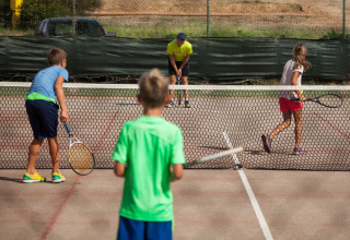 Børn spiller tennis på banen i Camping Village Baia Blu La Tortuga, en feriepark i Sardinien, Italien.