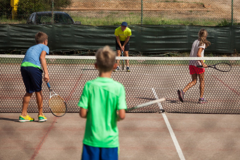 Børn spiller tennis på banen i Camping Village Baia Blu La Tortuga, en feriepark i Sardinien, Italien.