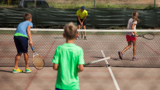Niños jugando al tenis en Camping Village Baia Blu La Tortuga, un parque vacacional en Cerdeña, Italia.