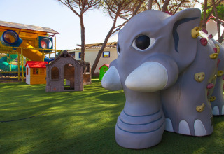 Legeplads med elefantskulptur, klatrevæg og legehuse ved Camping Village Baia Blu La Tortuga i Sardinien.