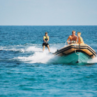 Persona practicando wakeboard detrás de una lancha inflable cerca de Aglientu, Cerdeña, Italia, día soleado.