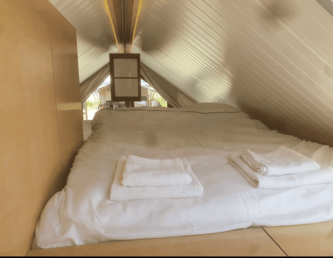 Acogedor dormitorio tipo loft con techo inclinado bajo en la cabaña Pentagon de Buytenplaets Suydersee, Países Bajos.