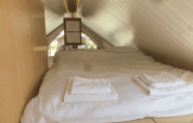 Acogedor dormitorio tipo loft con techo inclinado bajo en la cabaña Pentagon de Buytenplaets Suydersee, Países Bajos.