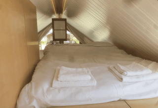 Acogedor dormitorio tipo loft con techo inclinado bajo en la cabaña Pentagon de Buytenplaets Suydersee, Países Bajos.