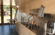Interior de cocina moderna con armarios de madera, estufa de gas, hervidor y cafetera en la lodge Pentagon.