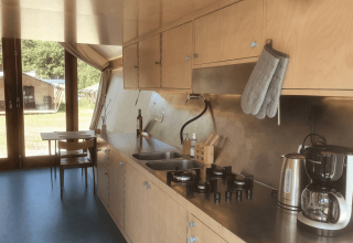 Interior de cocina moderna con armarios de madera, estufa de gas, hervidor y cafetera en la lodge Pentagon.