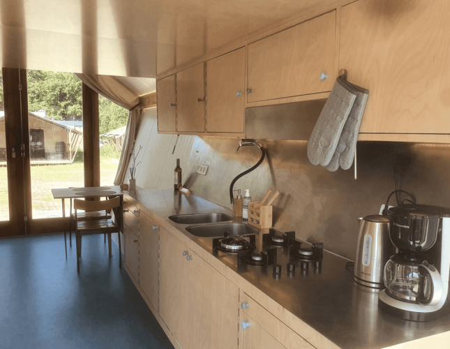 Moderne keuken met houten kasten, gasfornuis, waterkoker en koffiezetapparaat in Pentagon-lodge, Nederland.