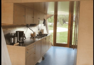 Moderne keuken in de Pentagon-lodge aan Buytenplaets Suydersee, Nederland, met houten kasten en uitzicht.