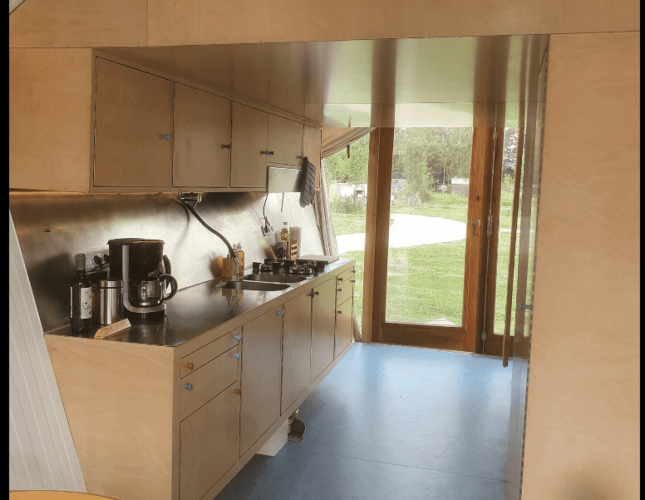 Cocina moderna en la cabaña Pentagon de Buytenplaets Suydersee, Países Bajos, con muebles de madera y vista.