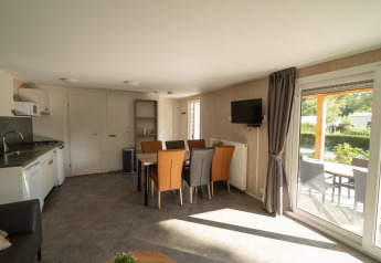 Foto interna di un lodge con zona pranzo, soggiorno, cucina e vista su un terrazzo coperto esterno.