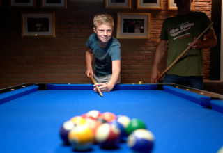 Junge spielt Billard mit einem Erwachsenen im Ferienpark Eurocamping Vessem BV, Nordbrabant, Niederlande.