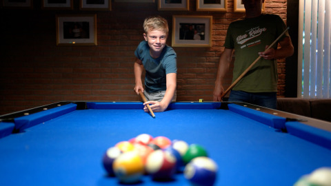 Dreng spiller billard med en voksen på et feriecenter, Eurocamping Vessem BV, Nordbrabant, Holland.