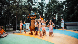 Niños juegan con una mascota de oso sobre un cojín hinchable en Eurocamping Vessem BV, Holanda.