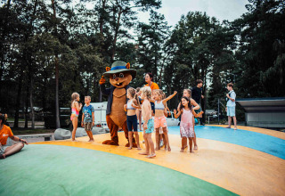 Bambini giocano con una mascotte orso su un cuscino gonfiabile a Eurocamping Vessem BV, Olanda.
