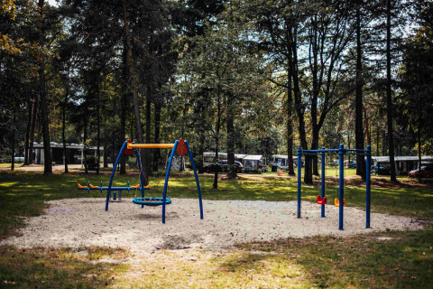 Spielplatz im Wald bei Eurocamping Vessem BV, Ferienpark in Nordbrabant, Niederlande mit Schaukeln.