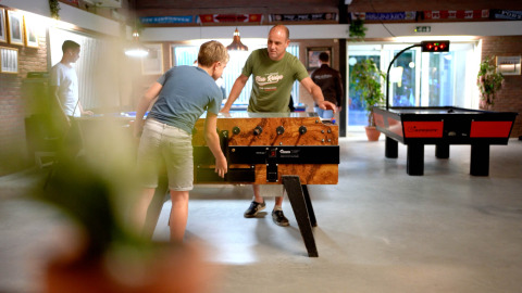 Mensen spelen tafelvoetbal en airhockey in de recreatieruimte bij Eurocamping Vessem BV, Noord-Brabant.
