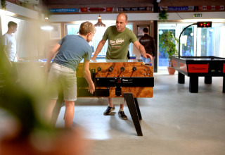 Mensen spelen tafelvoetbal en airhockey in de recreatieruimte bij Eurocamping Vessem BV, Noord-Brabant.