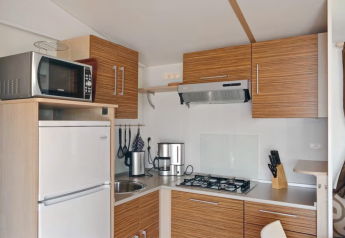 Cuisine moderne dans SunLodge Aspen Combi au Camping Leï Suves en France, avec plaques, armoires et appareils.