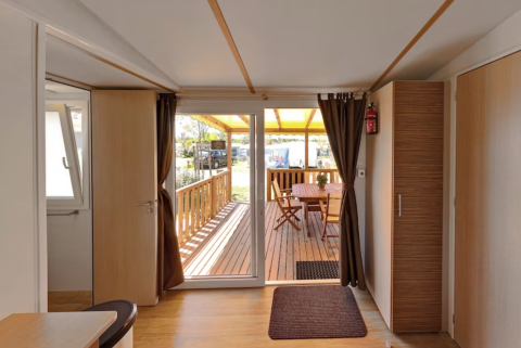 View from inside SunLodge Aspen Combi at Camping Leï Suves in France with terrace and outdoor dining.