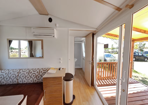 Bright interior of SunLodge Aspen Combi with view of terrace at Camping Leï Suves in France.