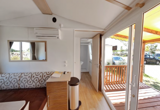 Bright interior of SunLodge Aspen Combi with view of terrace at Camping Leï Suves in France.