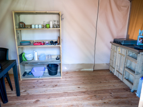 Area cucina in una tenda safari al Camping Elbeling in Germania con scaffale e utensili da cucina.