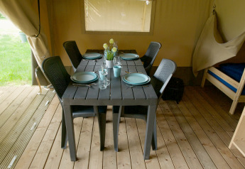 Eettafel gedekt voor vier in een safaritent bij Camping Elbeling, Duitsland, met houten vloer zichtbaar.