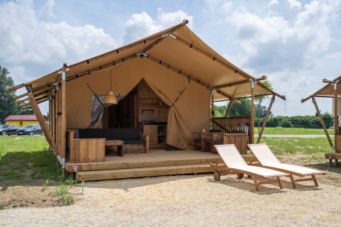 SunLodge Taiga : Grande tente glamping avec terrasse en bois, salon de jardin et deux transats.