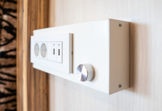 Primer plano de un panel de enchufes moderno con puertos USB y perilla en SunLodge BigLeaf en Italia.