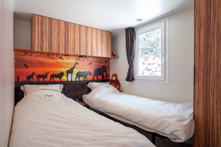 Habitación infantil con dos camas individuales, mural de animales y ventana en SunLodge BigLeaf, Camping Cisano/San Vito.