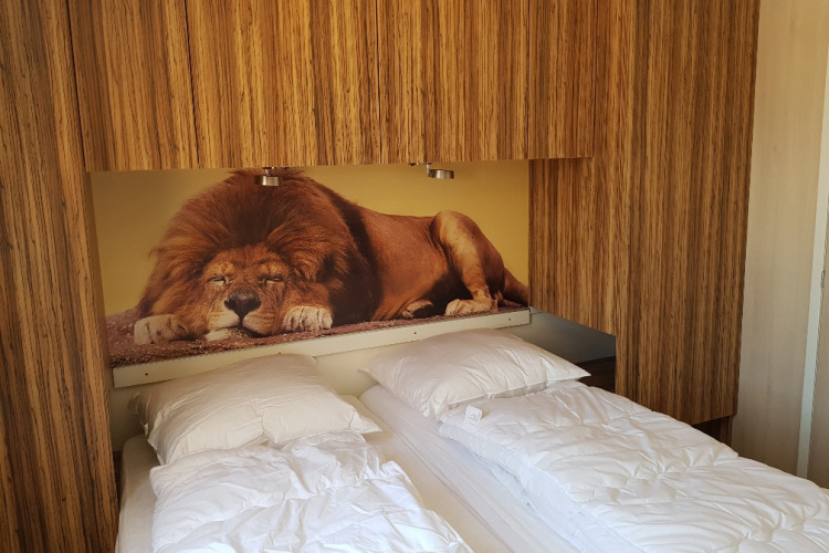 Habitación en SunLodge BigLeaf en Camping Cisano/San Vito, Italia, con mural de león sobre la cama.