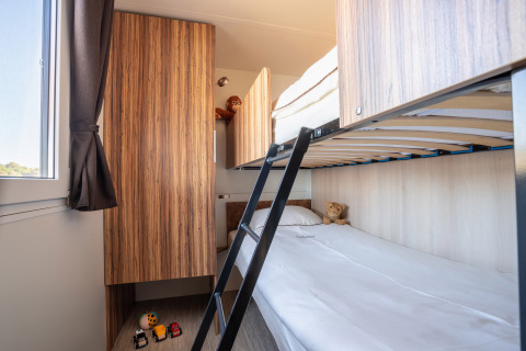 Habitación infantil con literas, muebles de madera y juguetes en SunLodge BigLeaf en Camping Cisano/San Vito, Italia.