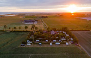 Solnedgang over Camping 'de Val' i Zeeland, Holland med marker, campingvogne og det fredelige landskab.